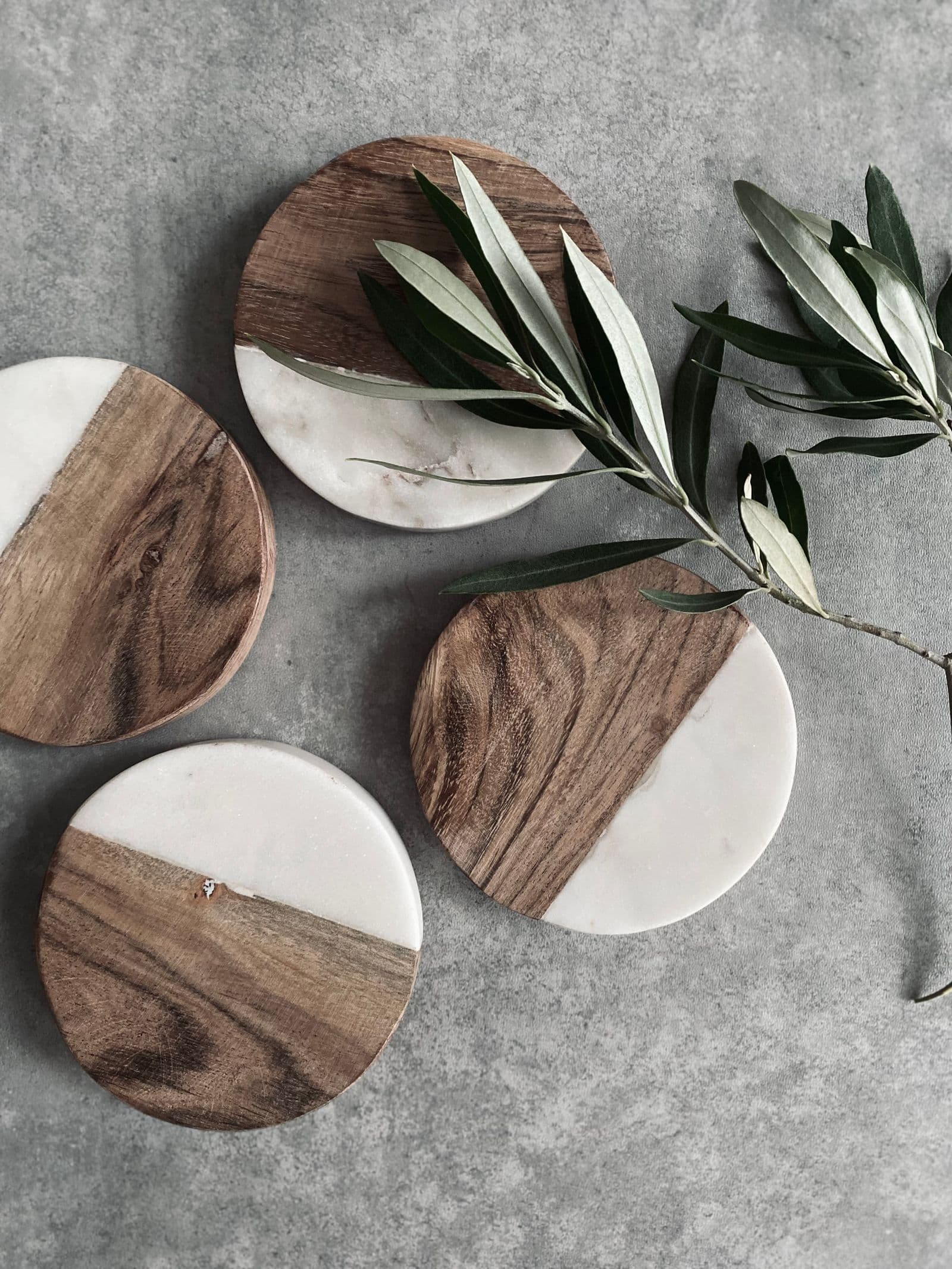 Round marble and acacia wood coasters with an olive branch