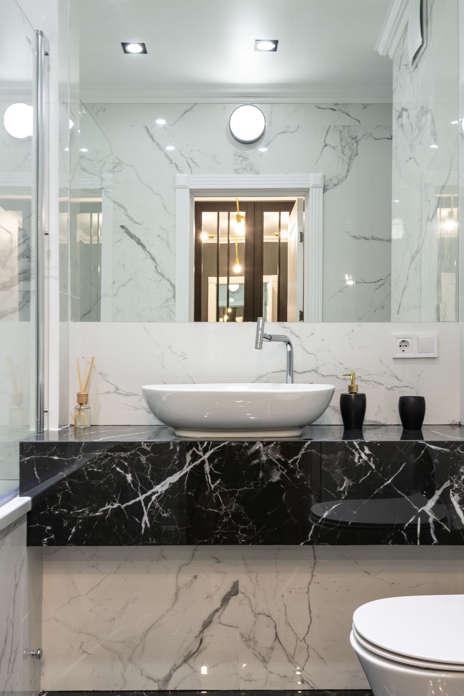 Black marble curb and counter in a white marble bathroom